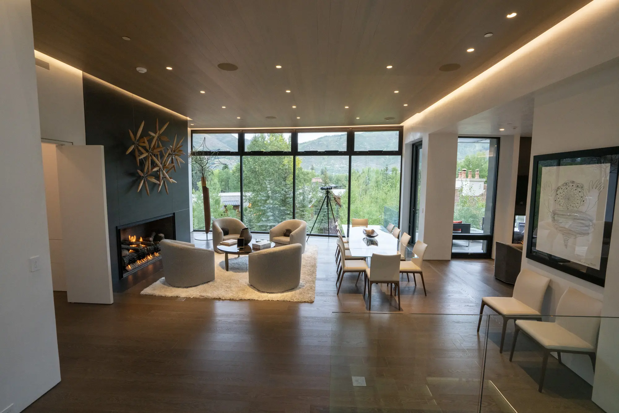 Open-concept living and dining area with large windows, a fireplace, whole-home audio speakers in the ceiling, and a mountain view.