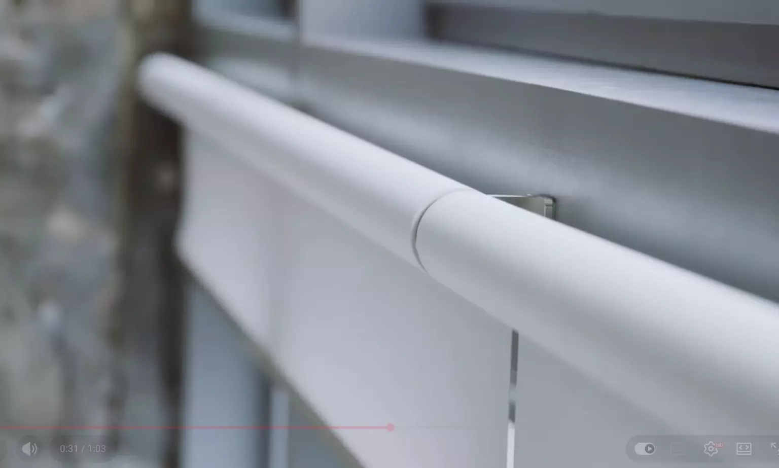 A close-up of a white roller blind installed on a window